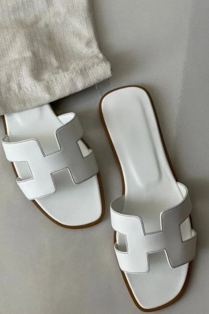 Gros plan sur les mules plates femme, bride en H distinctive. Chaussures d'été confortables et chic.