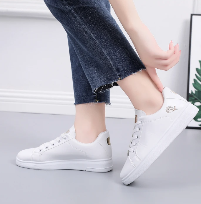 Femme portant des baskets blanches brodées fleurs, légères et respirantes, pour un look casual chic.
