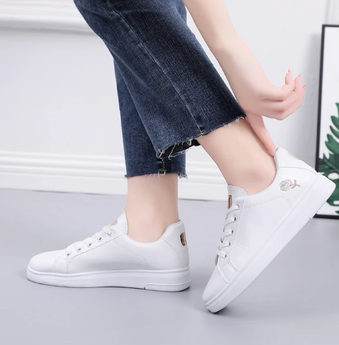 Gros plan sur les broderies florales délicates des baskets blanches femme, confort et style assurés.
