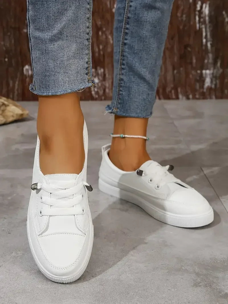 Chaussures sportives plates pour femmes, blanches à lacets, parfaites pour un style polyvalent et décontracté.