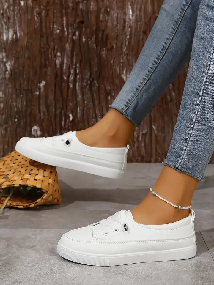 Baskets femmes blanches à lacets, bout rond. Confortables et plates, elles offrent un style décontracté et moderne.