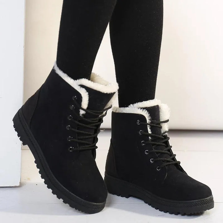 Femme portant des bottines chaudes en daim, imperméables et antidérapantes, marchant sur un chemin enneigé.