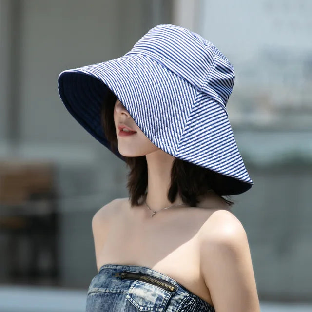 Élégant chapeau seau anti-UV réversible femme, motifs rayés noir et marine, accessoire mode essentiel pour l'été.