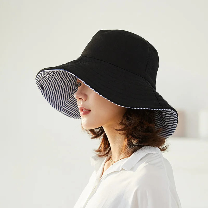 Protection solaire: Chapeau seau réversible anti-UV pour femme, design rayé noir/marine, parfait pour un look chic en été.