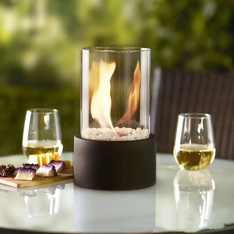 Cheminée portable moderne, design épuré, verre cylindrique, base métal noir. Ambiance chaleureuse.