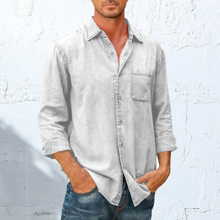 Homme portant une chemise boutonnée décontractée, manches longues, look intemporel et élégant.
