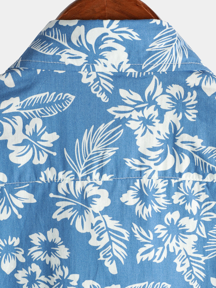 Détail d'une chemise homme fleurie avec des motifs hawaïens, couleurs vives, texture légère.