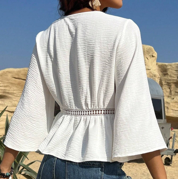 Chemisier fluide femme bohème blanc avec col V et manches évasées, parfait pour un look estival décontracté chic.
