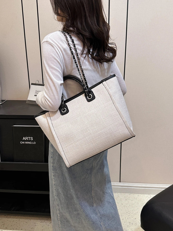 Femme utilisant un grand sac cabas élégant en toile, idéal pour le shopping ou le travail. Sac porté épaule pratique.