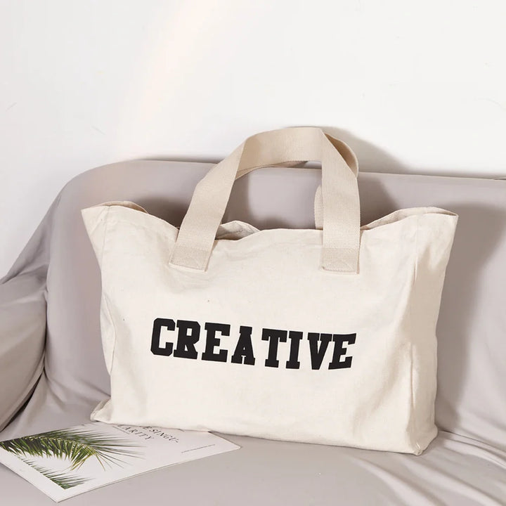 Grand sac de plage en tissu crème pour femme, idéal pour l'été et les voyages.