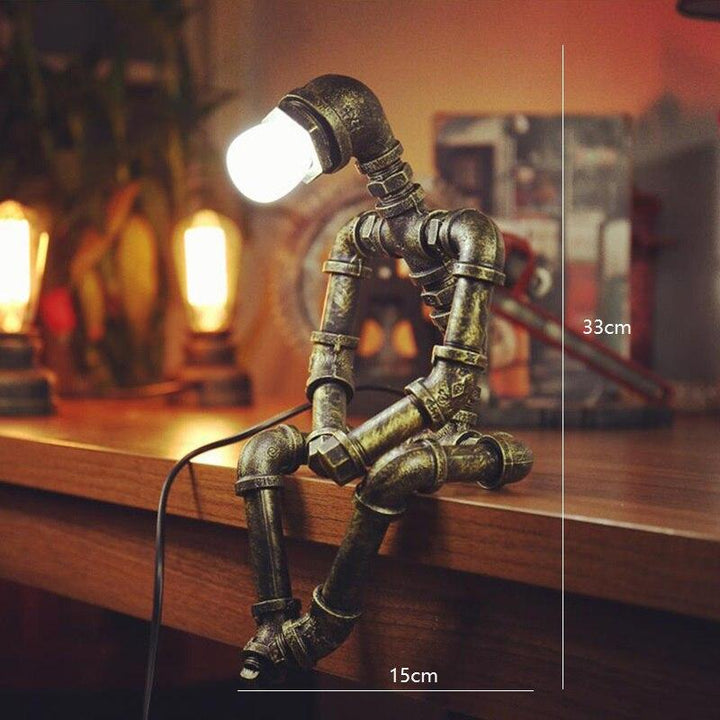 Lampe robot industrielle en fer, style rétro chic, bras et tête ajustables, finition laiton, design tuyaux industriels.