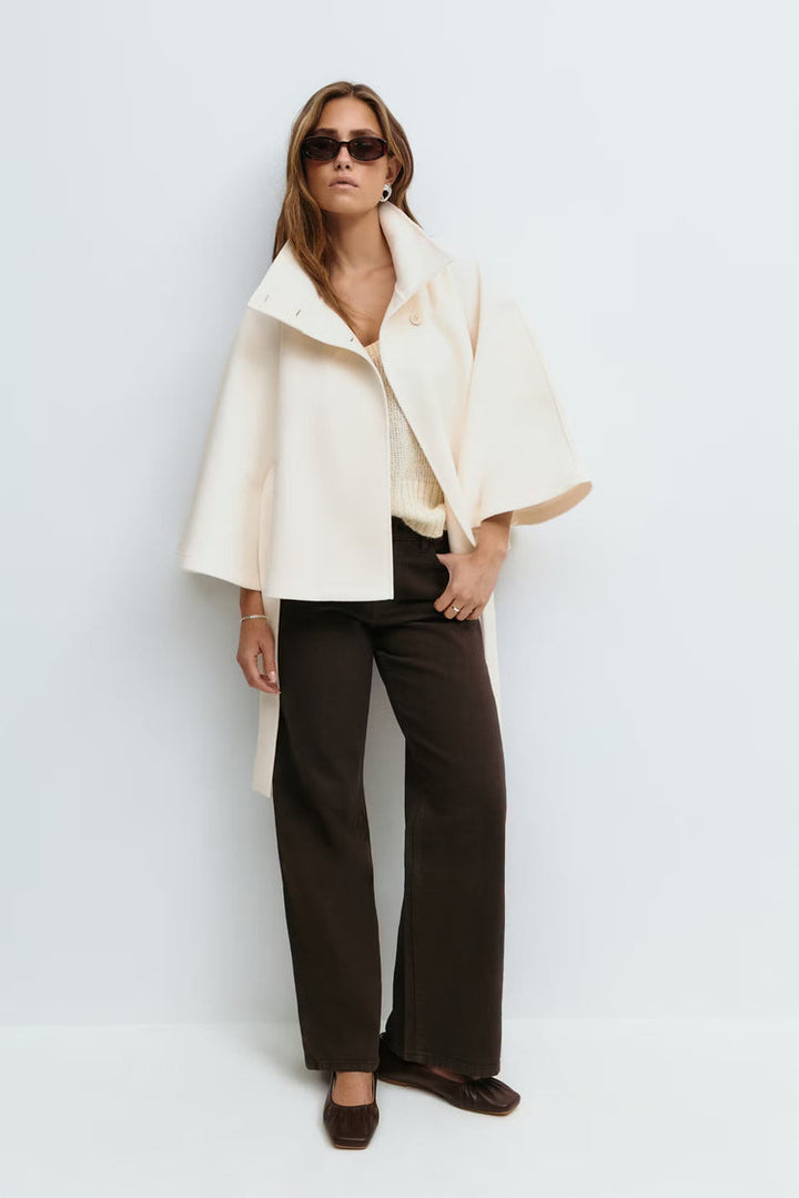 Manteau femme hivernal, coupe cape, col montant, ceinturé, pour une allure distinguée.