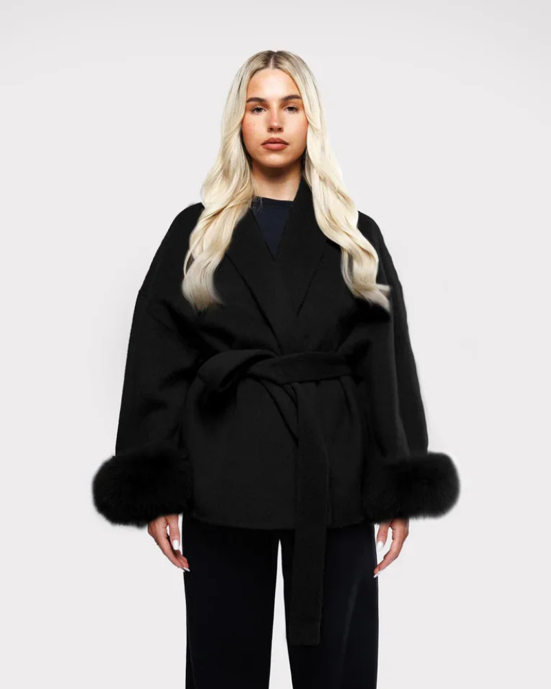 Manteau femme élégant noir avec manches en fausse fourrure et ceinture chic. Parfait pour l'hiver.