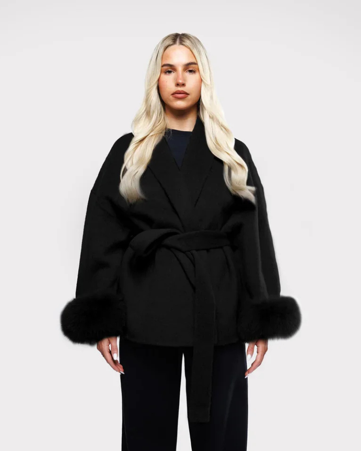 Manteau femme élégant noir avec manches en fausse fourrure et ceinture chic. Parfait pour l'hiver.