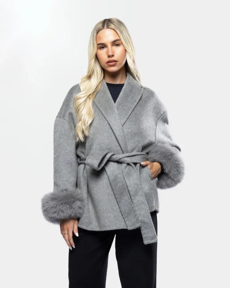Veste longue hiver sophistiquée pour femme avec ceinture et détails en fausse fourrure. Chaude et confortable.