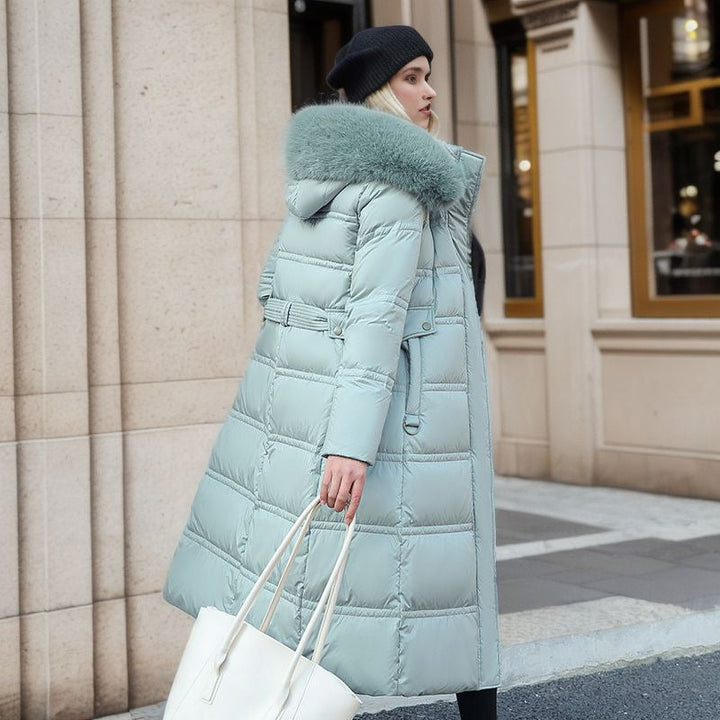 Silhouette féminine en manteau long matelassé, chaud et élégant, avec col fourrure pour l'hiver.