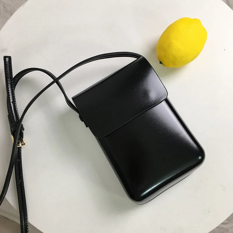 Femme moderne portant un mini sac bandoulière téléphone noir, accessoire mode polyvalent pour un look chic.