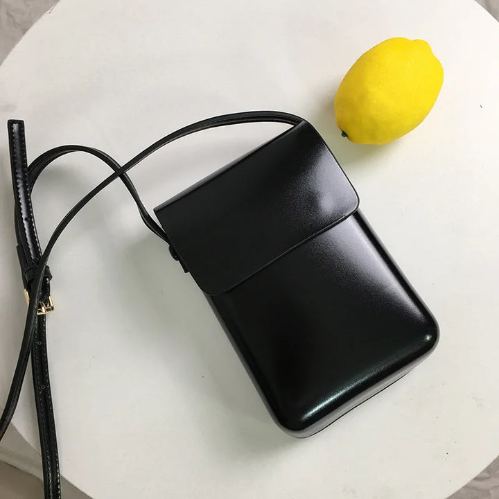 Femme moderne portant un mini sac bandoulière téléphone noir, accessoire mode polyvalent pour un look chic.