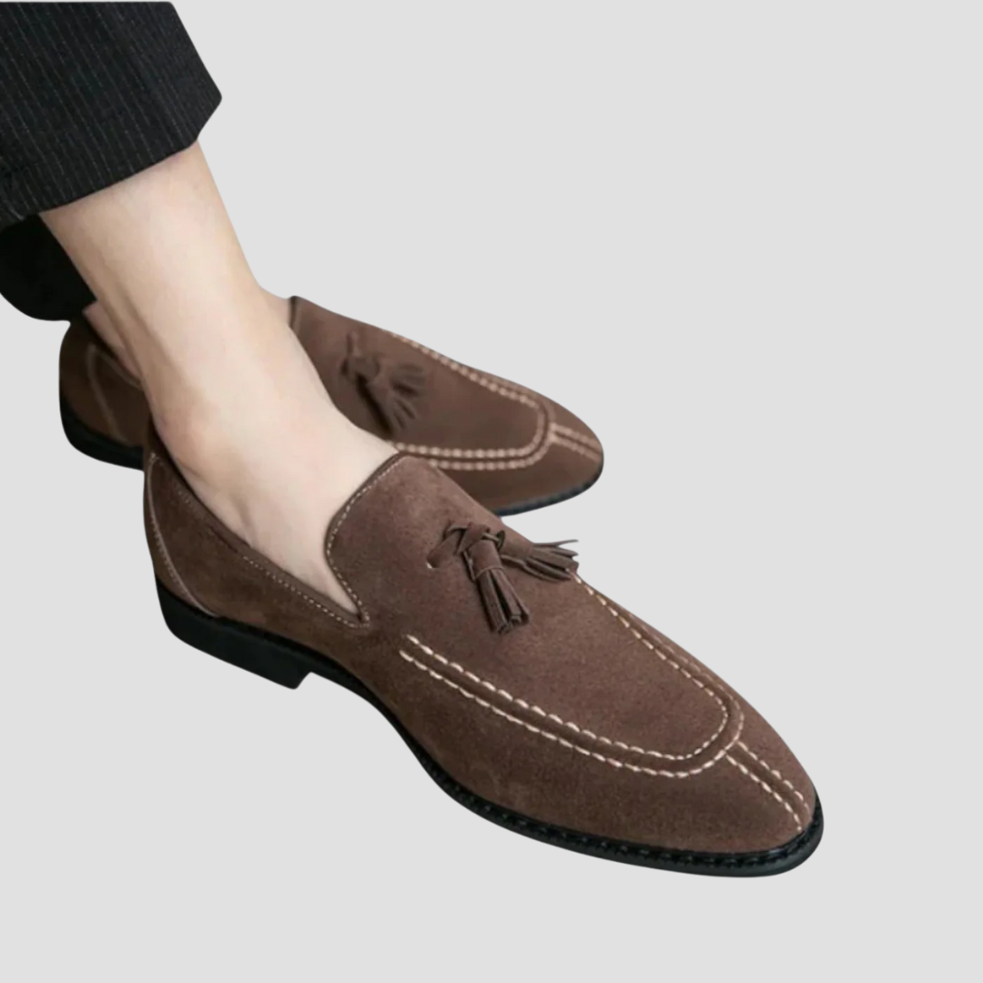"Mocassins en daim pour homme, vue latérale, couleur marron avec pampilles élégantes, semelle caoutchouc, style raffiné."