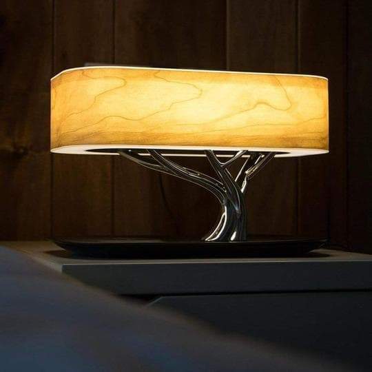 Modern tree-shaped desk lamp with wireless charging & Bluetooth speaker. Adjustable light, elegant design.