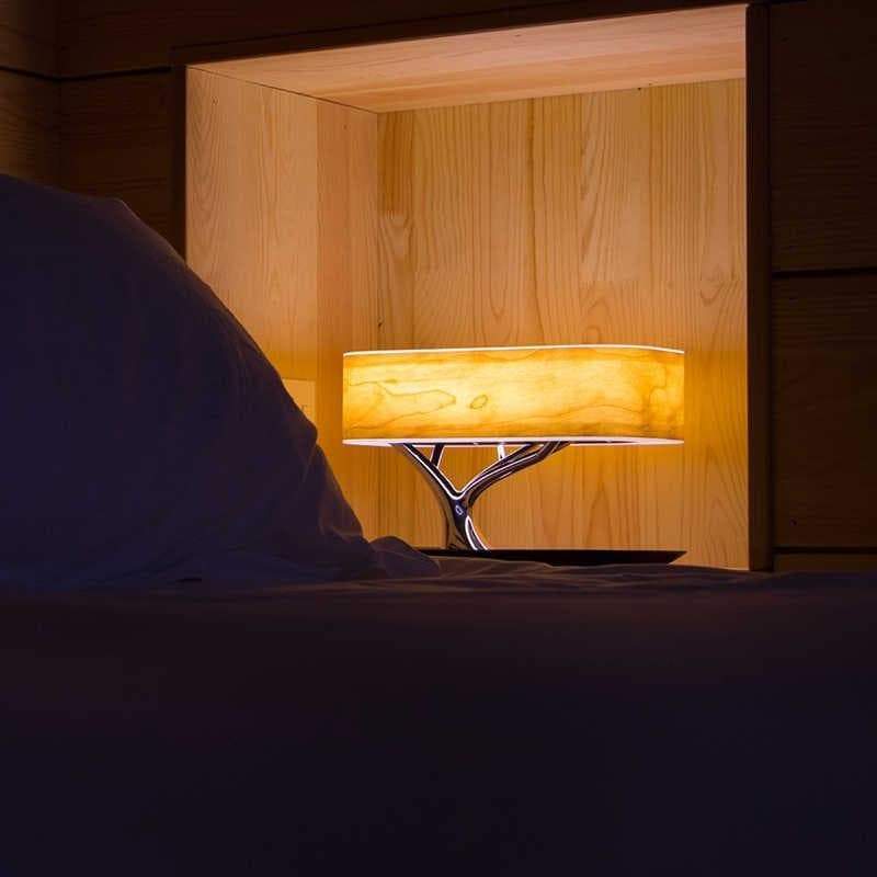 Modern tree-shaped desk lamp with wireless charging & Bluetooth speaker. Adjustable light, elegant design.