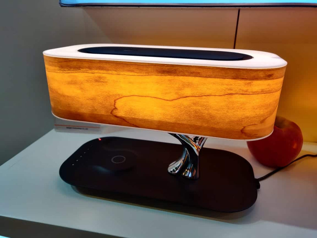 Modern tree-shaped desk lamp with wireless charging & Bluetooth speaker. Adjustable light, elegant design.