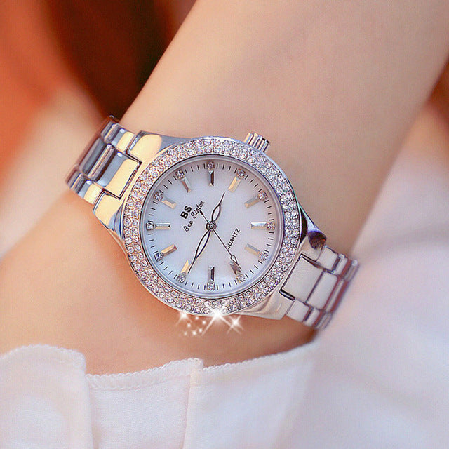 Montre pour femme ornée de strass, cadran nacre iridescent, bracelet métal bicolore argenté et doré, style élégant.