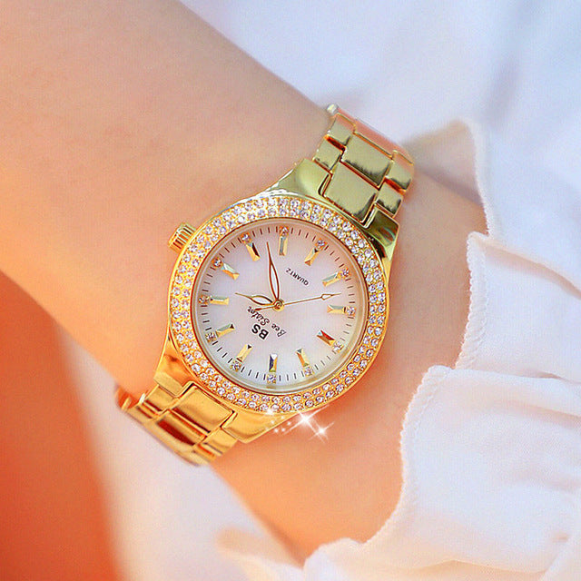 Montre pour femme ornée de strass, cadran nacre iridescent, bracelet métal bicolore argenté et doré, style élégant.