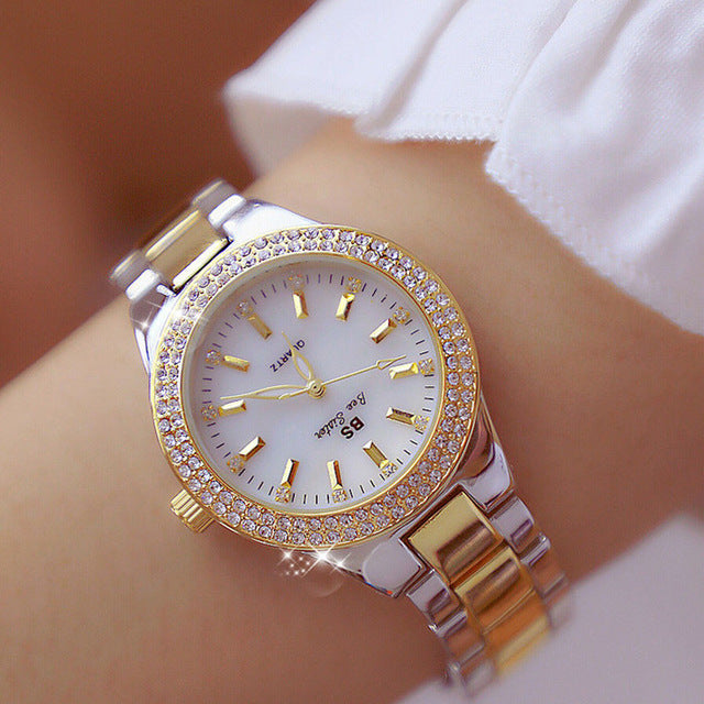 Montre pour femme ornée de strass, cadran nacre iridescent, bracelet métal bicolore argenté et doré, style élégant.