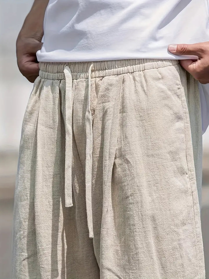 Mode homme: pantalon décontracté ample en lin kaki, essentiel pour les loisirs estivaux et le bien-être.