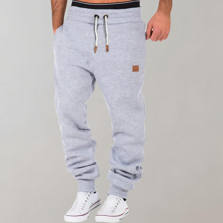 Pantalon de jogging homme gris confortable pour le sport ou la détente, style athleisure moderne.