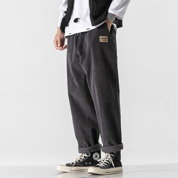 Gros plan sur la texture du pantalon homme en velours côtelé noir. Tissu doux et confortable pour l'hiver décontracté.