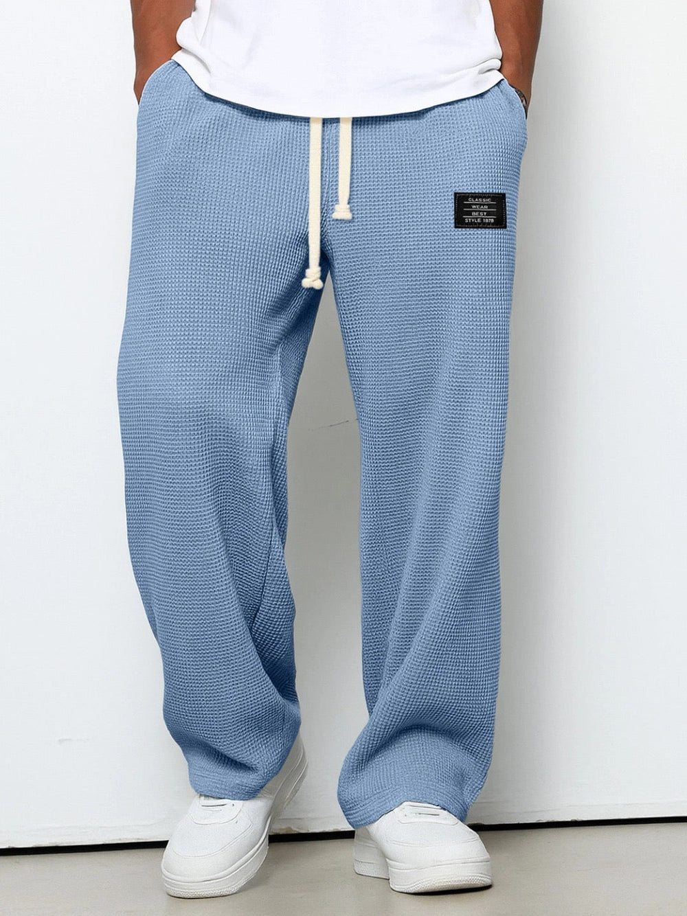 Gros plan sur la texture gaufrée d'un pantalon homme ample, style casual, parfait pour l'été.