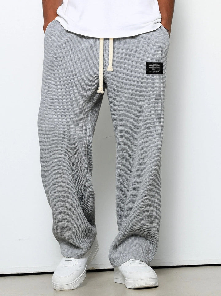 Pantalon homme couleur sable, coupe ample et décontractée, texture gaufrée, style jogger.