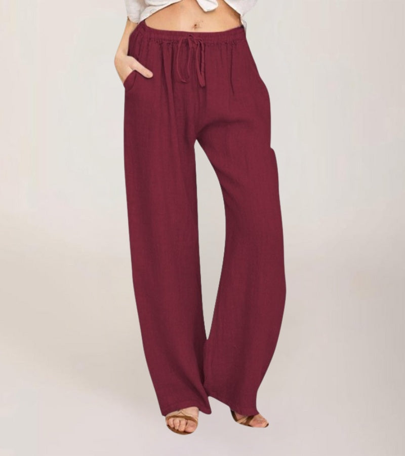 Femme marchant sur la plage, vêtue d'un pantalon fluide en lin décontracté d'été, style vacances.