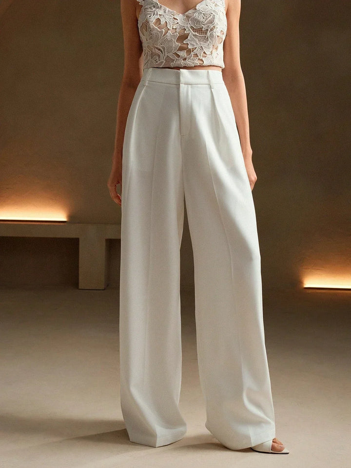 Femme portant un pantalon large plissé taille haute, look chic et décontracté, parfait pour le bureau.