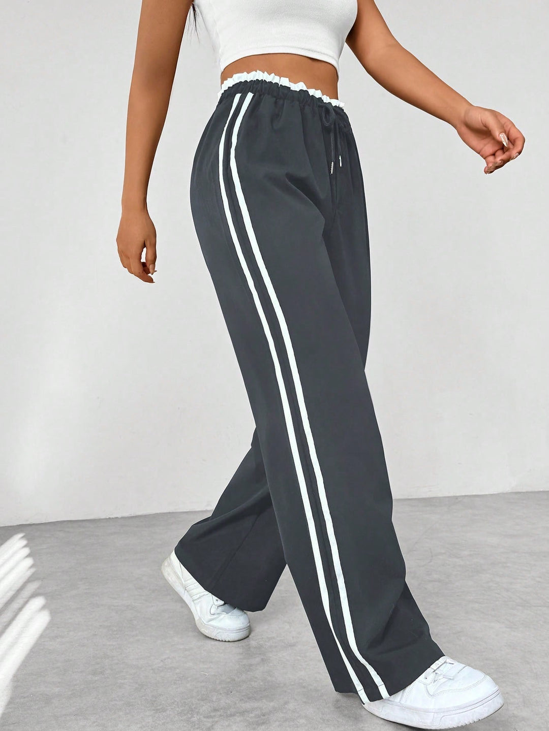 Pantalon large sportif femme noir à bandes latérales et taille élastique. Confort et style tendance pour loisirs.