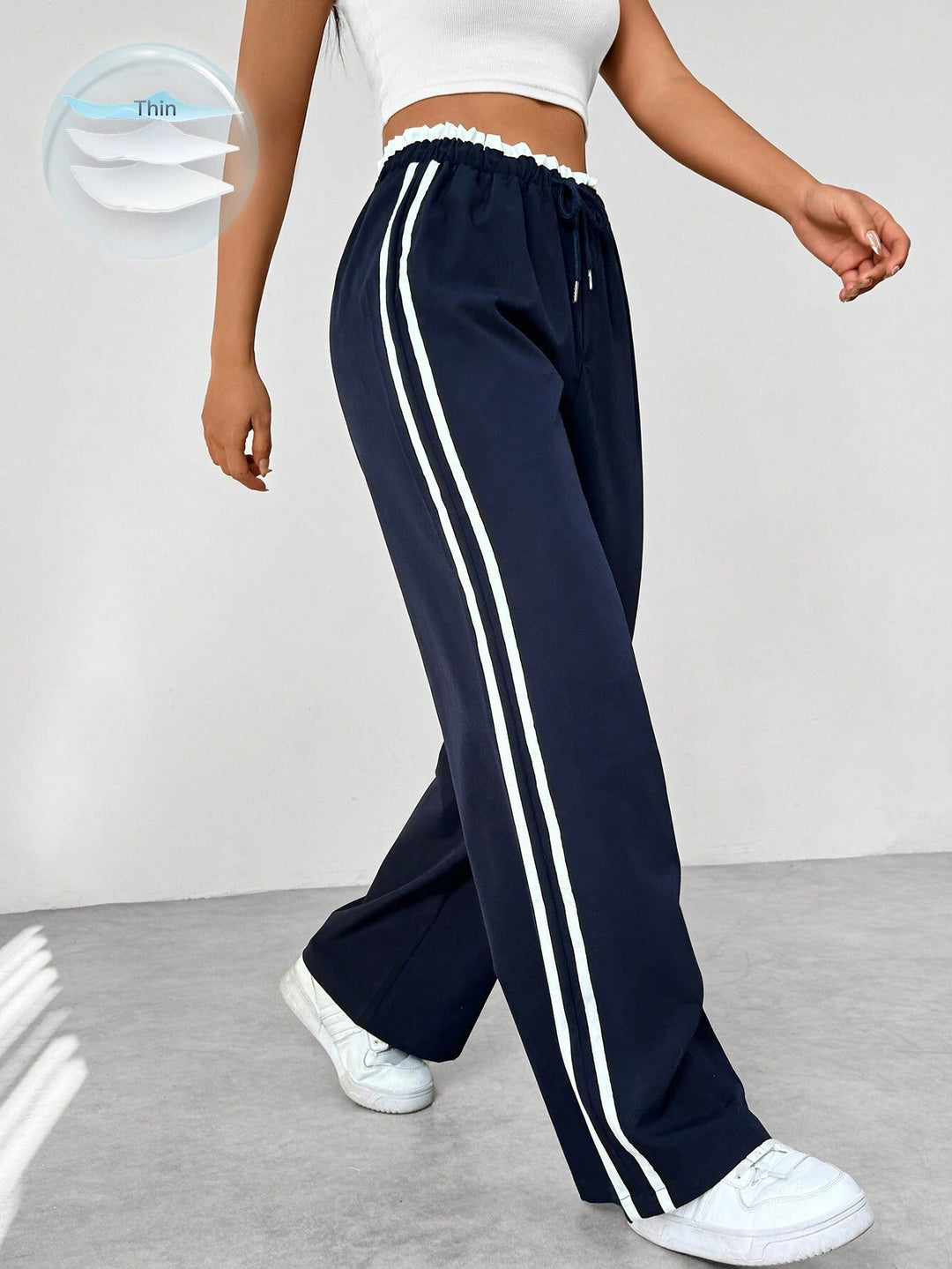 Pantalon femme sportif noir avec bandes latérales, coupe large et fluide. Style décontracté et confortable.