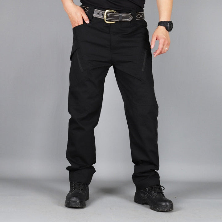 Homme en pantalon tactique stretch imperméable, marchant en randonnée, idéal pour l'aventure en extérieur.