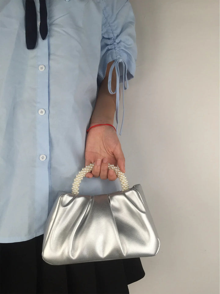 Accessoire soirée incontournable: sac à main petit format en satin lisse avec perles délicates.
