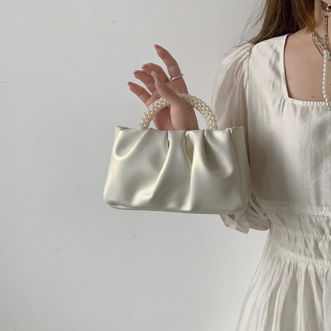Accessoire mariage féminin: petit sac à main perlé et satiné, couleur crème, très élégant.