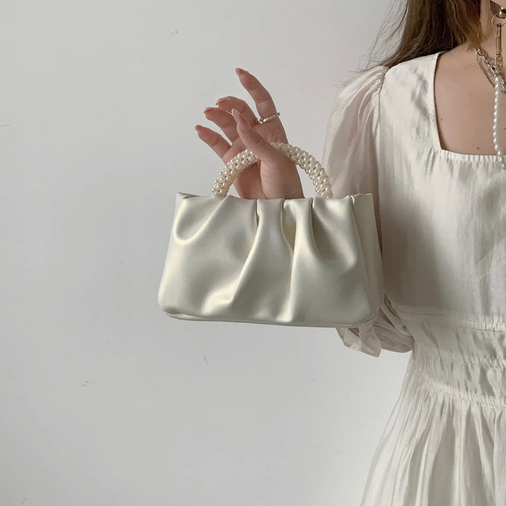 Accessoire mariage féminin: petit sac à main perlé et satiné, couleur crème, très élégant.