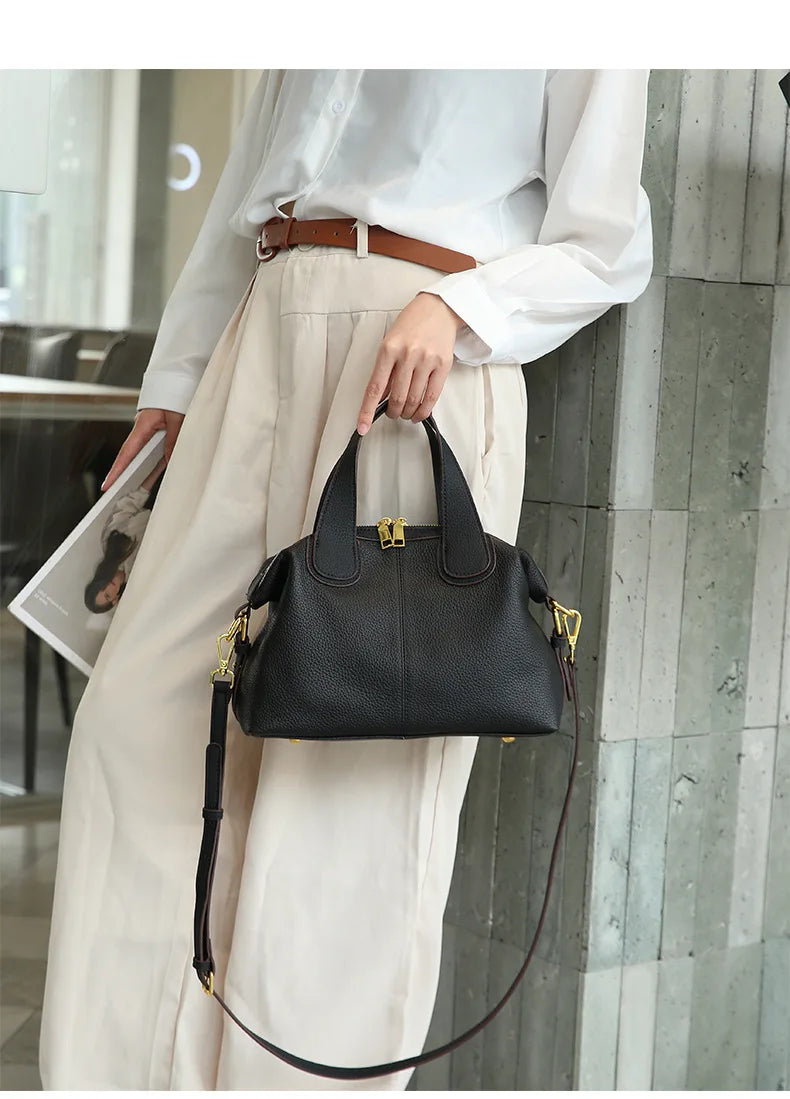 Vue de face d'un petit sac à main bandoulière femme, cuir fendu gris beige, design épuré.