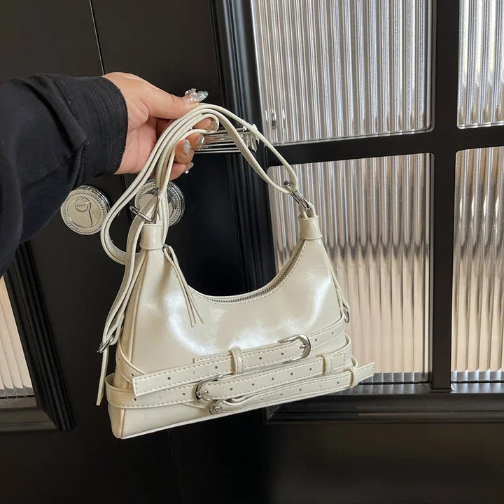 Modèle portant un petit sac à main noir tendance en similicuir, style rock chic, accessoire mode femme.