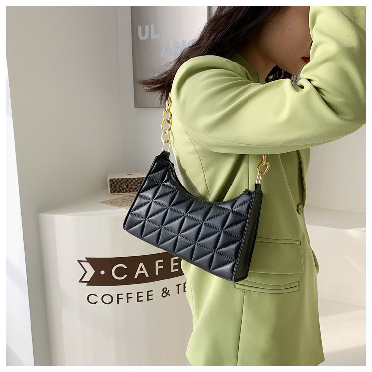Accessoire féminin: petit sac noir avec chaînette dorée, un ajout élégant pour toute tenue de soirée.