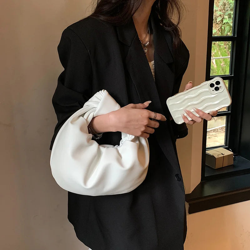 Petit sac à main rond en cuir synthétique noir, élégant et compact pour femme, parfait pour une soirée.