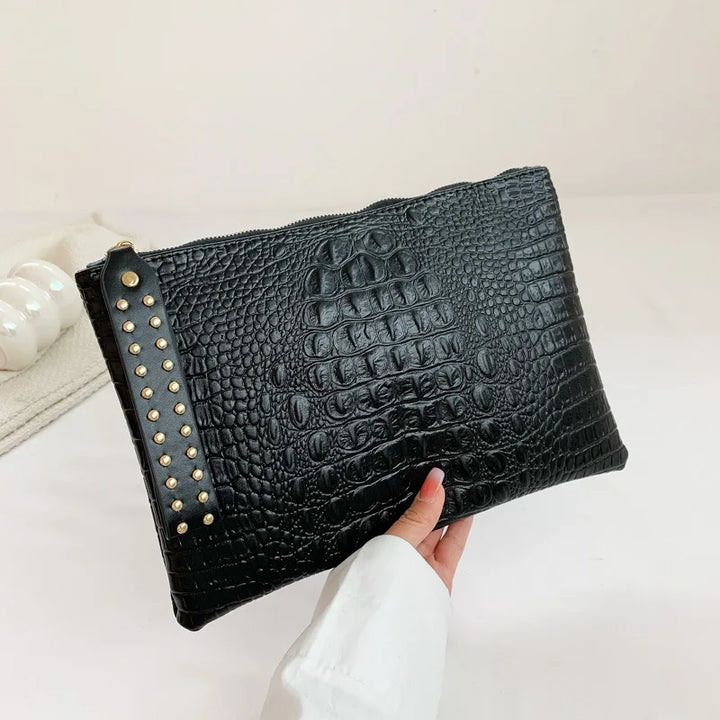 Pochette de soirée en similicuir noir élégante pour femme, avec ornement métallique.