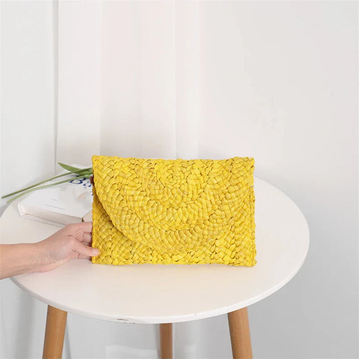 Détail d'une pochette femme en paille tressée, accessoire estival naturel et raffiné.