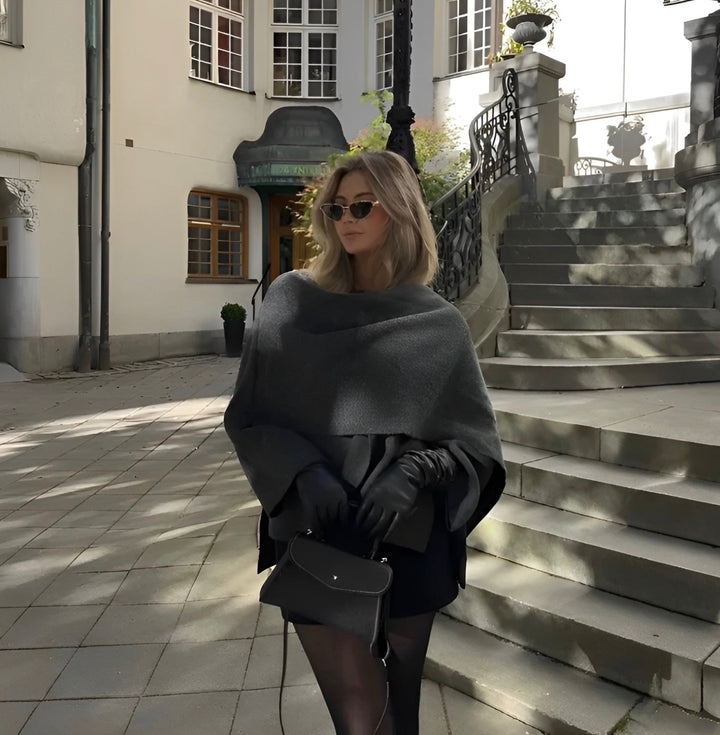 Femme portant un poncho asymétrique gris foncé, élégant et chaleureux. Parfait vêtement hiver tendance.
