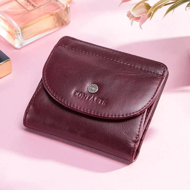 Vue de dessus d'un portefeuille compact en cuir pour femme, coloris bordeaux, montrant texture et surpiqûres fines.